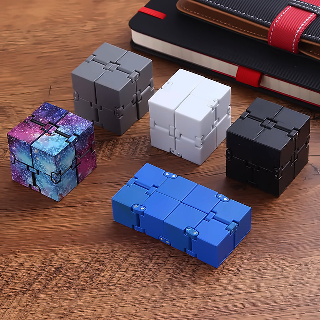 Infinity Cube fidget cubes in several colors arranged on a wooden desk
