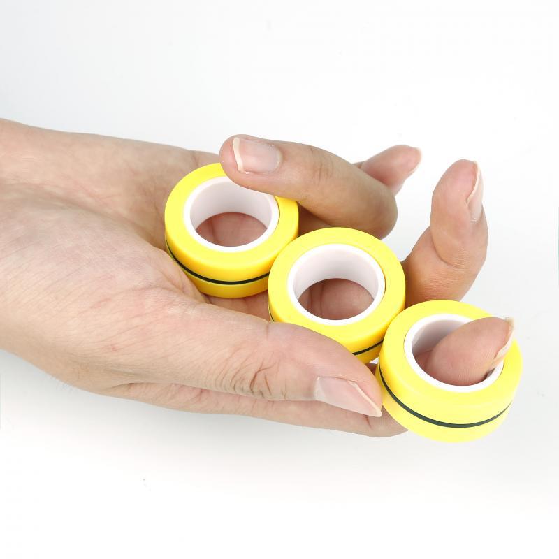 Magnetic Rings on fingers — yellow magnetic fidget rings held in hand
