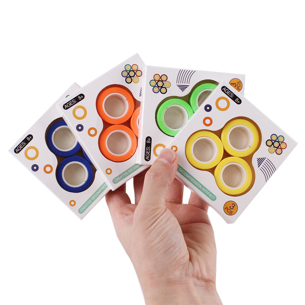 Hand holding Magnetic Rings boxes in blue, orange, green and yellow