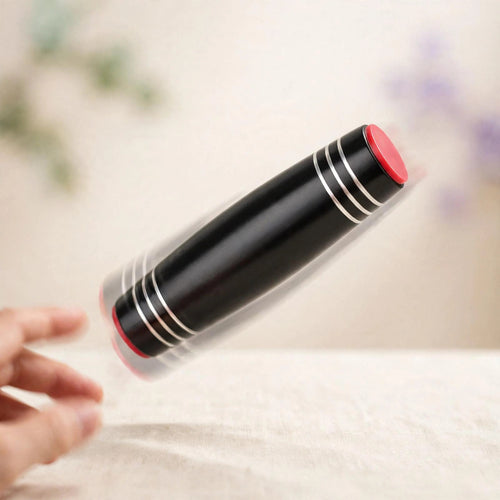 Flip Stick — black metal flip stick with red end caps tumbling mid-flip over a desk