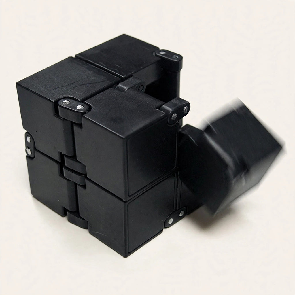 Infinity Cube — black fidget cube mid-flip on a cream background