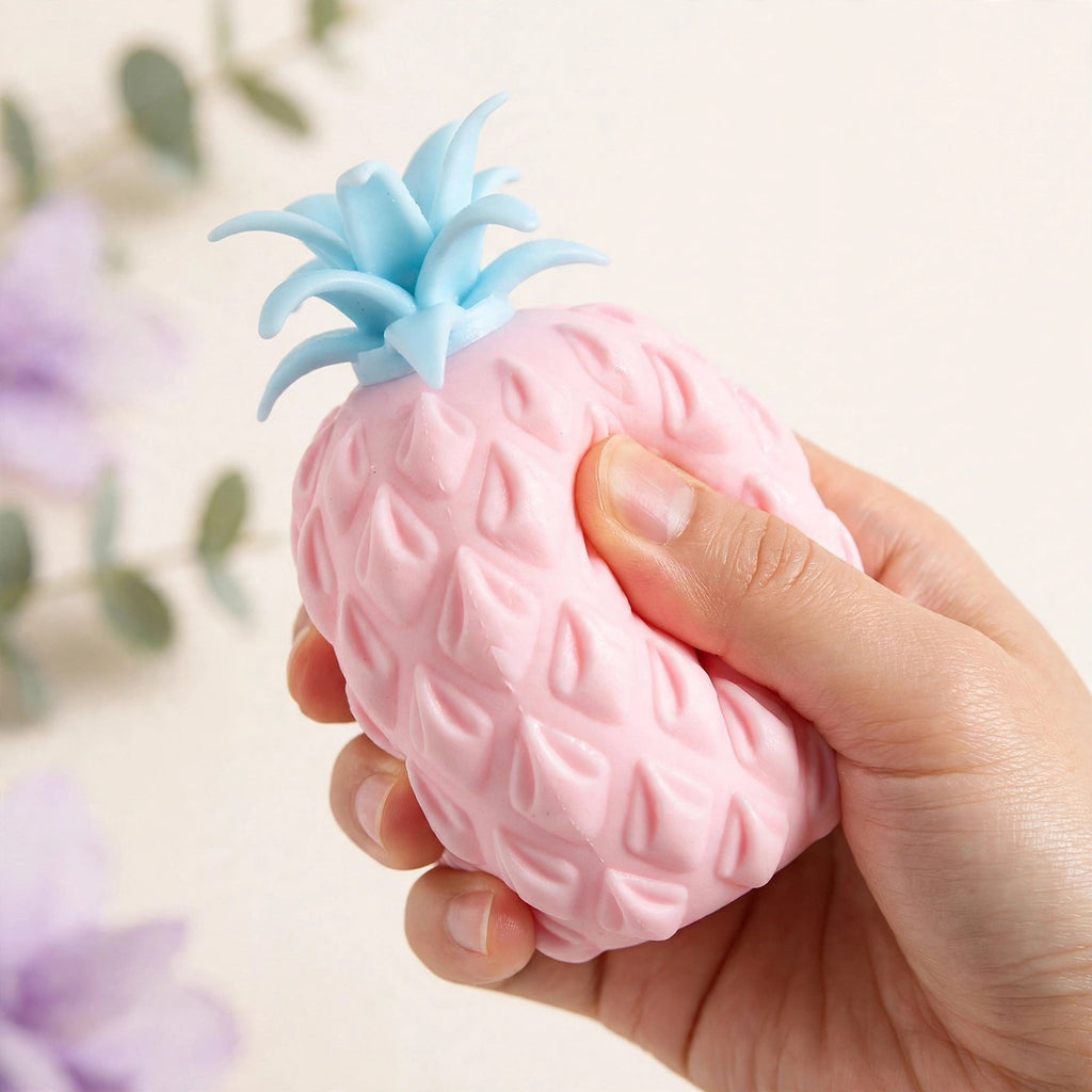 Pineapple Pop Ball — pink pineapple squeeze toy with a blue crown being gently squeezed by hand