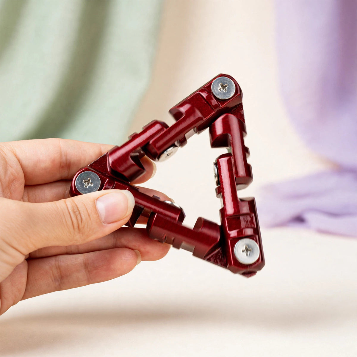 Roller Spinner — red metal triangle chain roller being rolled in hand